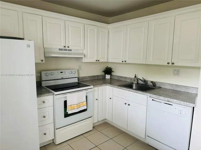a kitchen with granite countertop white cabinets and white appliances