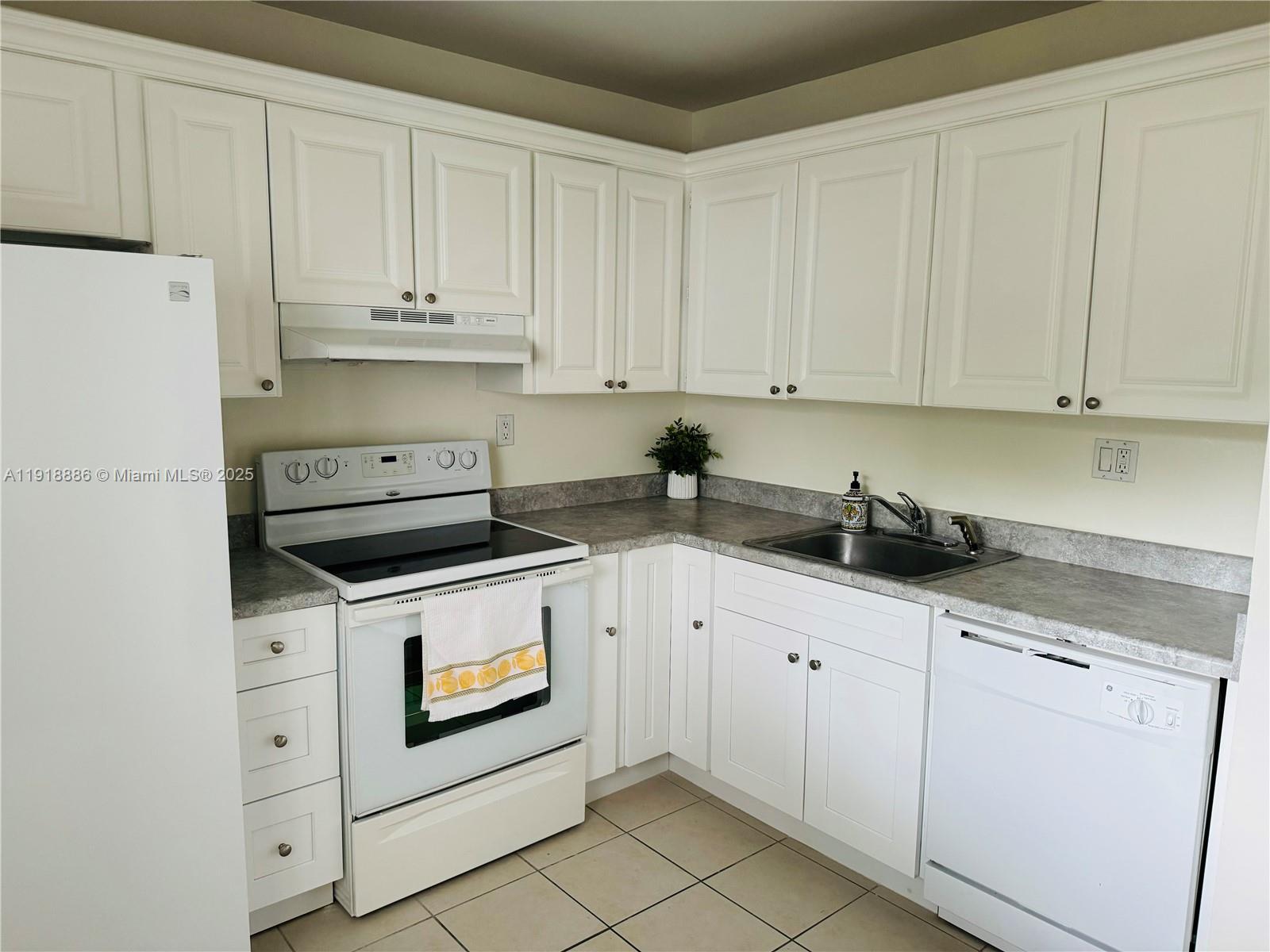 701 North Pine Island Road, Unit 101 Plantation, FL 33324 - Photo 9 of 31 a kitchen with granite countertop white cabinets and white appliances