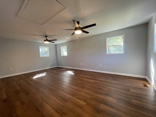 a view of empty room with wooden floor and fan