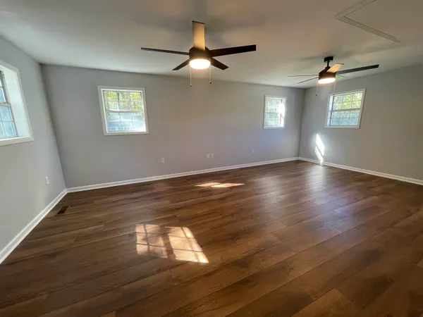 a view of empty room with wooden floor and fan