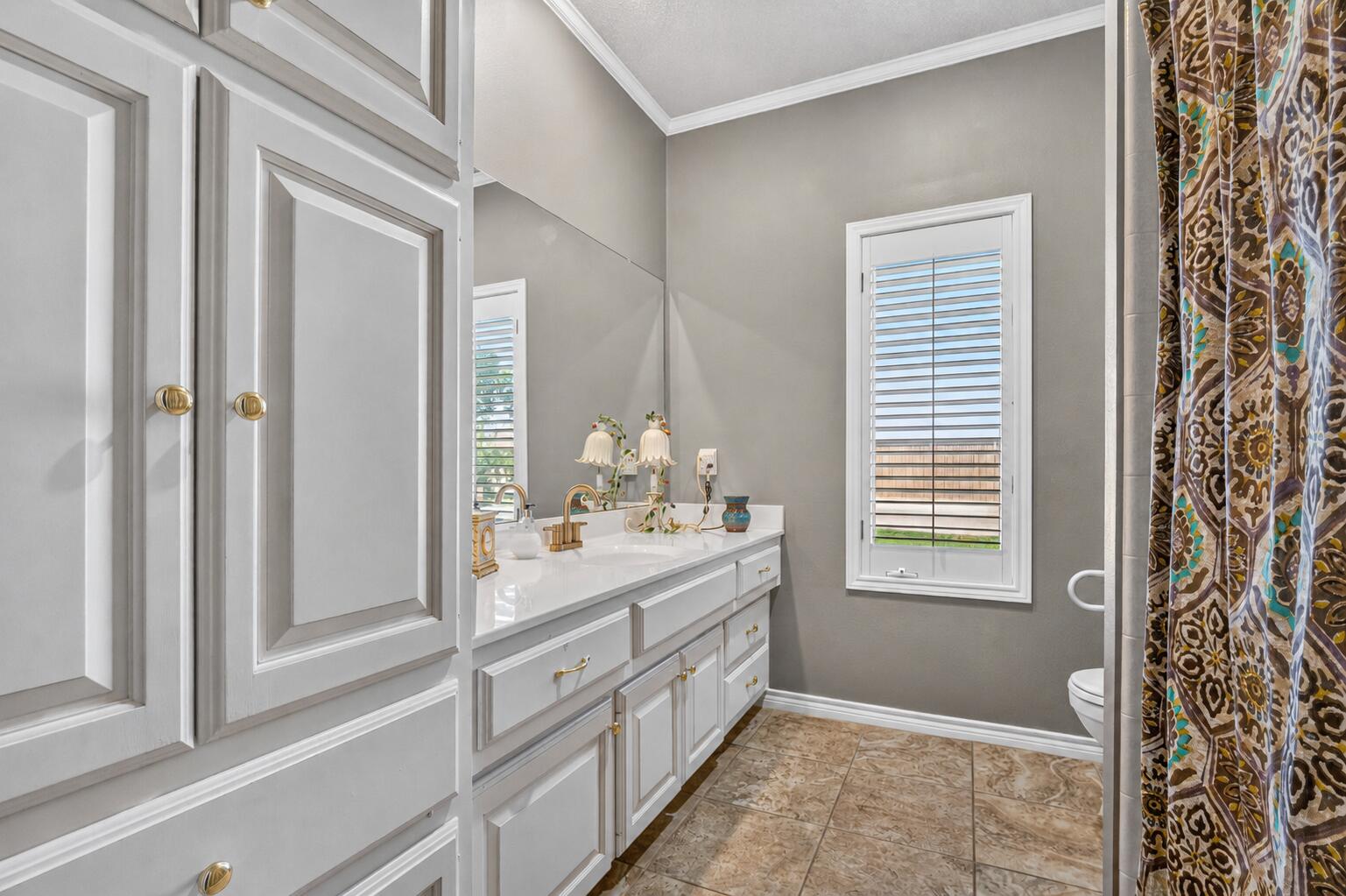 7402 95th Street Lubbock, TX 79424 - Photo 27 of 43 a bathroom with a double vanity sink a mirror and a bathtub
