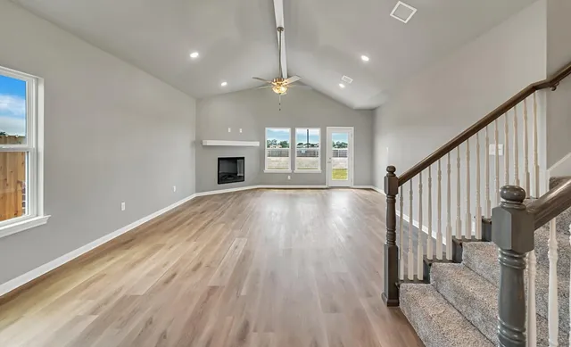 a view of an empty room with wooden floor fireplace and a window