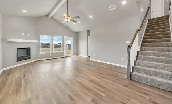 an empty room with wooden floor fan and windows
