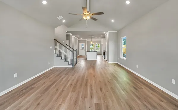 an empty room with windows and chandelier fan