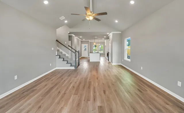 an empty room with windows and chandelier fan