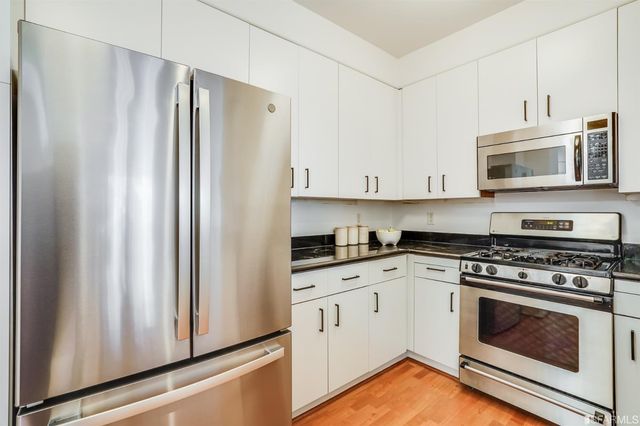 a kitchen with stainless steel appliances white cabinets white stove a microwave and a refrigerator