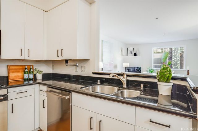 a kitchen with granite countertop a sink and white cabinets