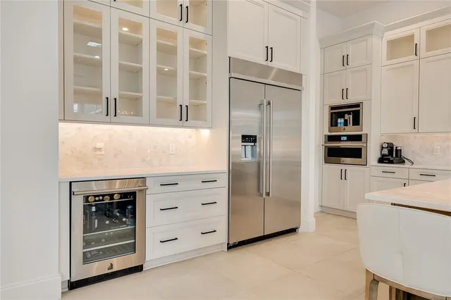 a large kitchen with cabinets chairs and wooden floor