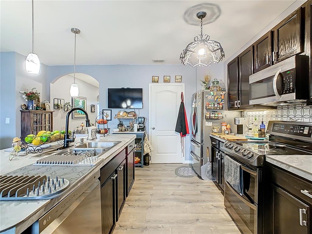 1765 Brockridge Road Kissimmee, FL 34744 - Photo 9 of 45 a kitchen with stainless steel appliances granite countertop a sink a stove and a wooden floors