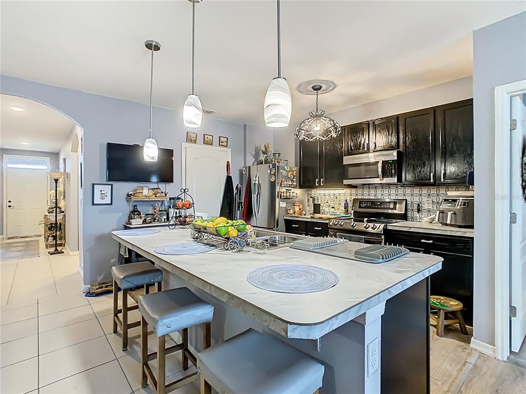 1765 Brockridge Road Kissimmee, FL 34744 - Photo 10 of 45 a kitchen with kitchen island a sink counter and chairs