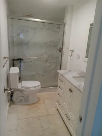 a bathroom with a granite countertop sink toilet and shower