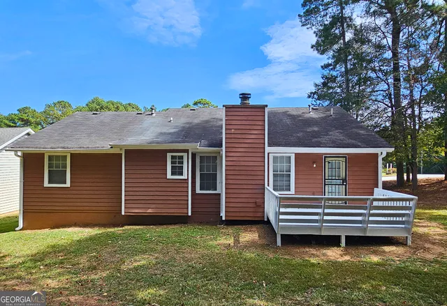 a backyard of a house with a bench and lawn chairs