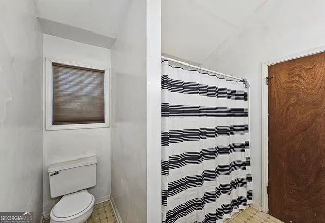 a bathroom with a toilet and a shower curtain