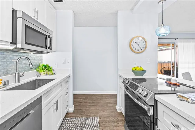 a kitchen with stainless steel appliances a sink a stove cabinets and a counter top space