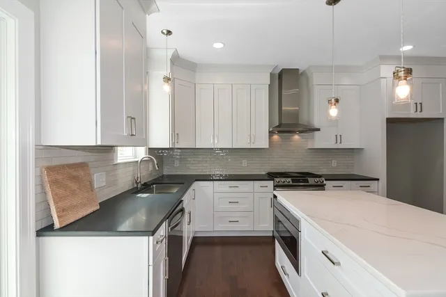 a large kitchen with stainless steel appliances granite countertop a sink a stove a refrigerator and island with wooden floor