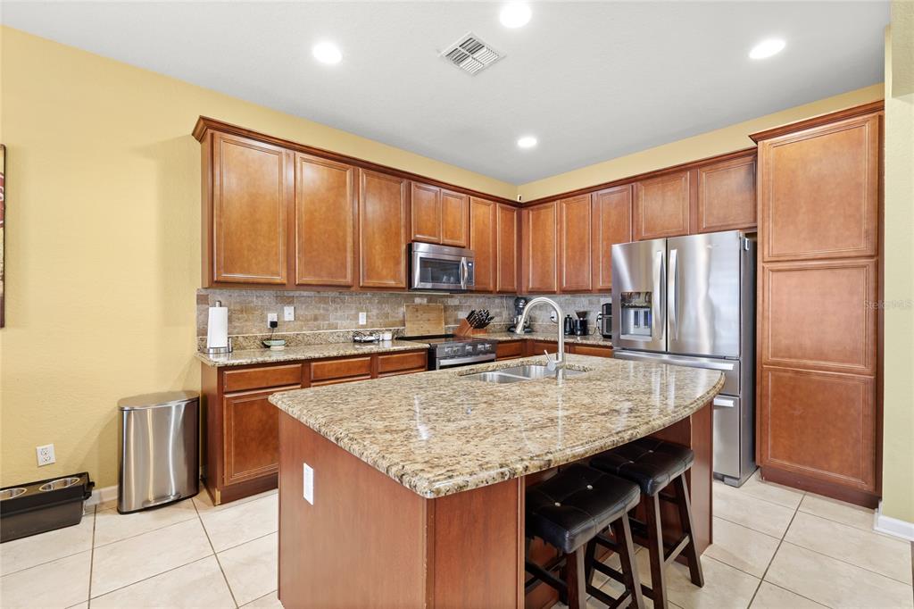 13243 Charfield Street Windermere, FL 34786 - Photo 17 of 39 a kitchen with granite countertop a refrigerator a stove a sink and a counter