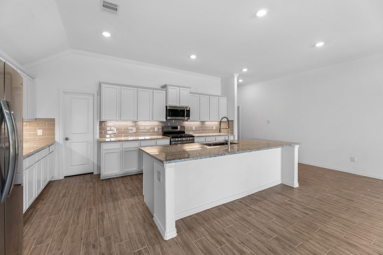 21714 Grayson Highlands Way Porter, TX 77365 - Photo 6 of 27 a kitchen with sink a wooden floor and white cabinets