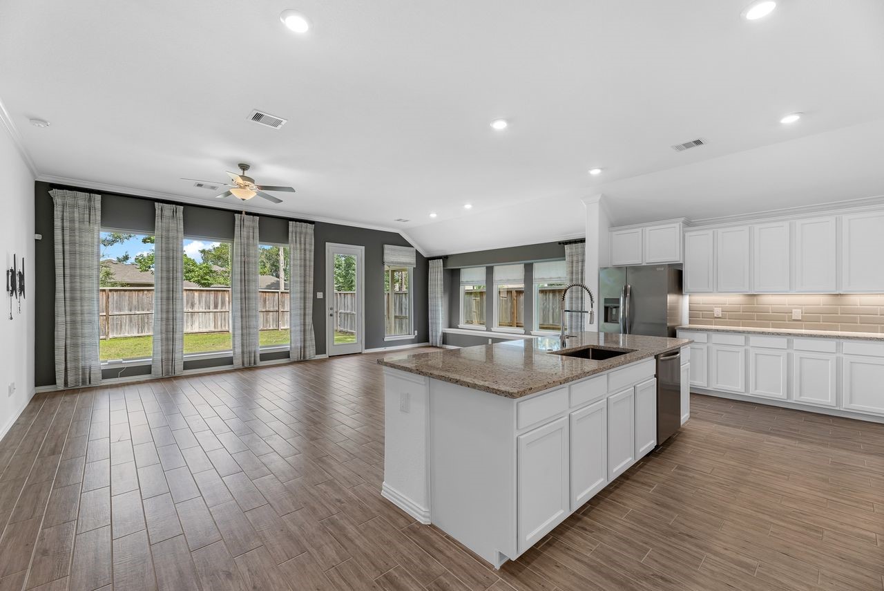 21714 Grayson Highlands Way Porter, TX 77365 - Photo 8 of 27 a large kitchen with stainless steel appliances kitchen island a large counter top and a wooden floors