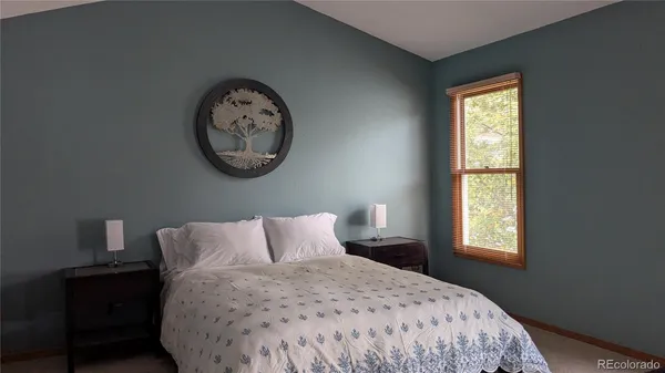 a bedroom with a bed and a lamp on dresser