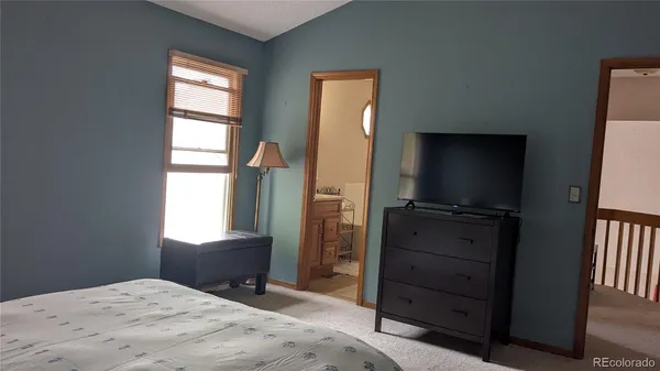 a bedroom with a bed and a flat tv screen on dresser