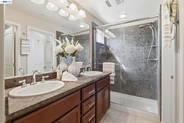 a bathroom with a shower sink vanity granite and mirror