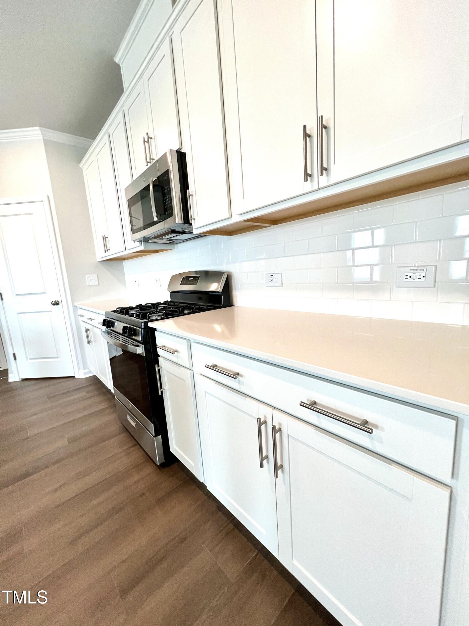 429 Lily Grv Loop Raleigh, NC 27610 - Photo 12 of 32 a kitchen with stainless steel appliances white cabinets and wooden floor