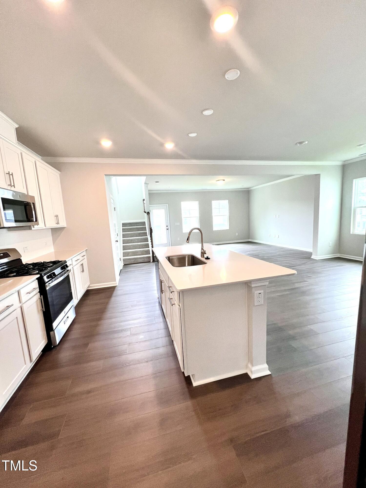 429 Lily Grv Loop Raleigh, NC 27610 - Photo 13 of 32 a large white kitchen with wooden floor and a sink