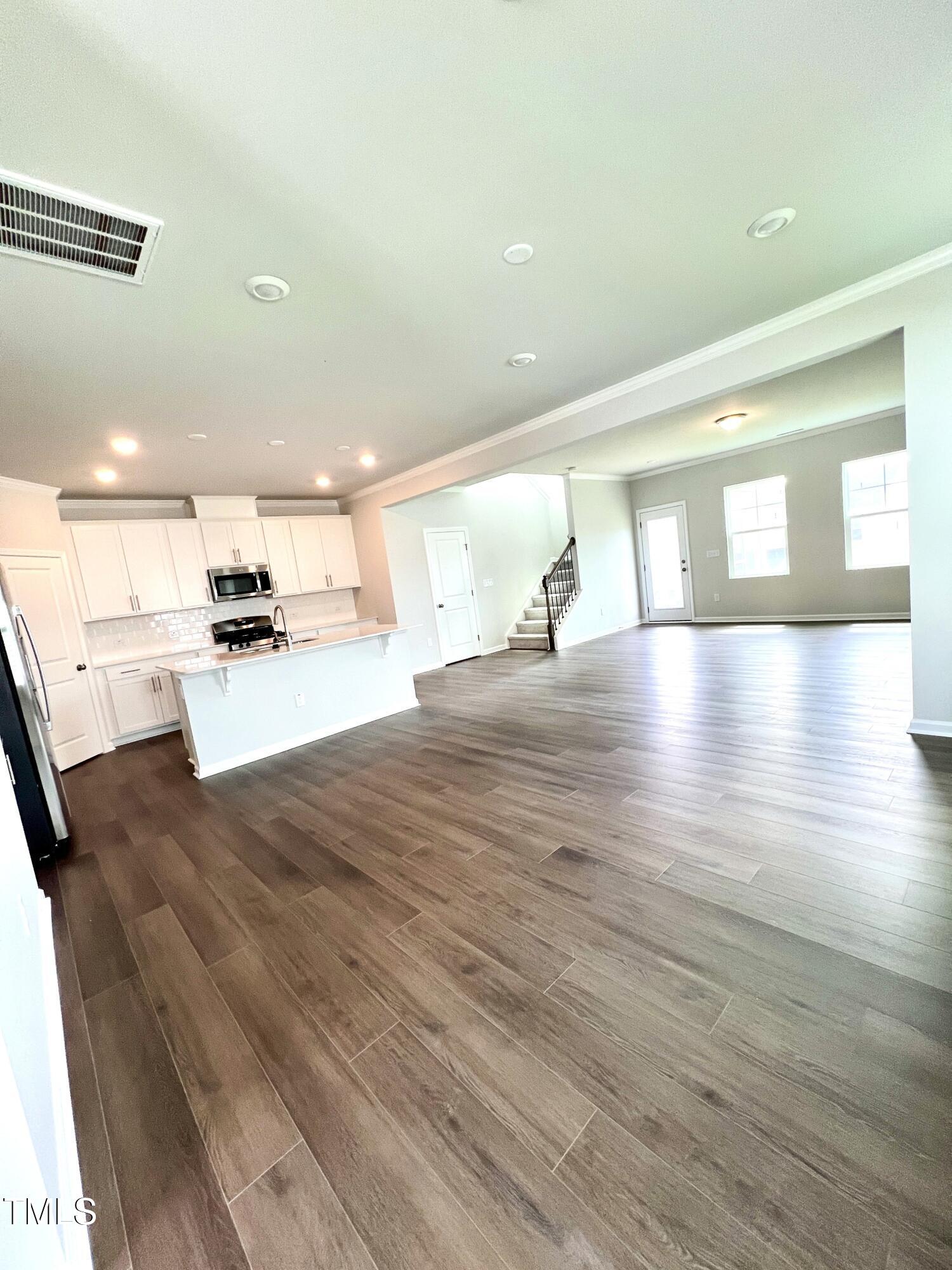 429 Lily Grv Loop Raleigh, NC 27610 - Photo 5 of 32 a view of a living room a kitchen with stainless steel appliances wooden floor and large windows