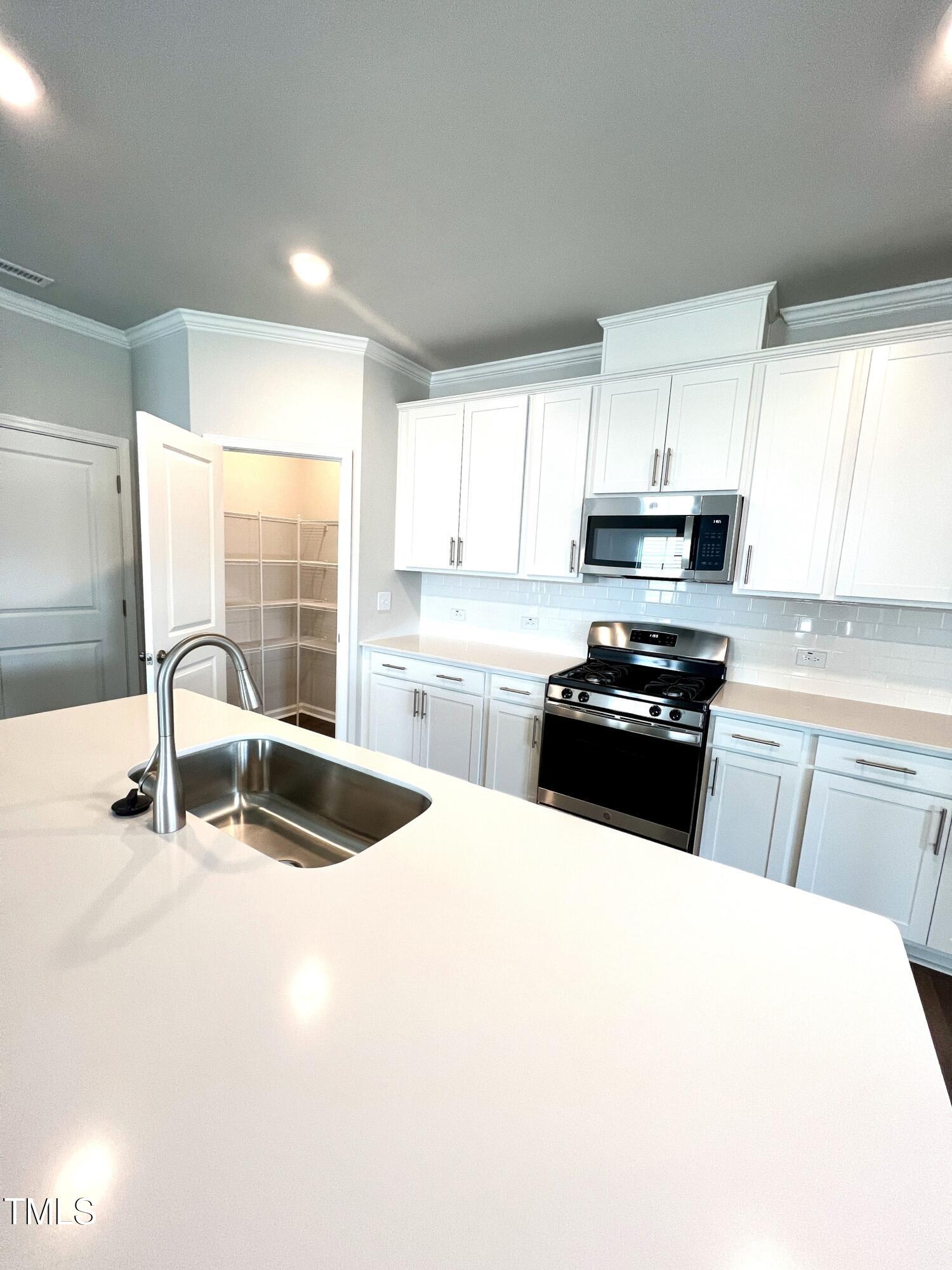 429 Lily Grv Loop Raleigh, NC 27610 - Photo 10 of 32 a kitchen with kitchen island a sink a stove a microwave and cabinets