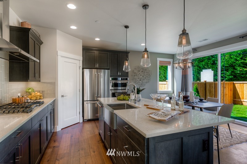 22263 9th Drive Southeast, Unit 9S Bothell, WA 98021 - Photo 8 of 25 a kitchen with stainless steel appliances kitchen island granite countertop a sink a stove a refrigerator and a dining table with wooden floor