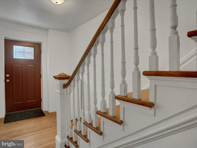 an empty room with fireplace wooden floor chandelier and windows