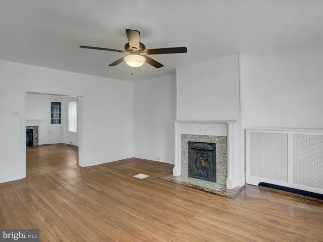 an empty room with wooden floor fireplace and windows