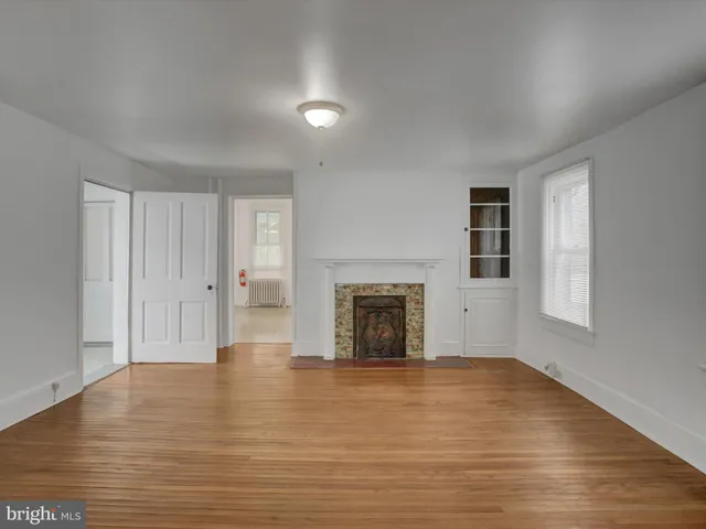 a view of an empty room with mirror and a hardwood