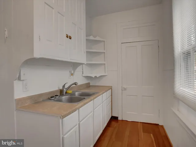 a view of a hallway with wooden floor and a bathroom