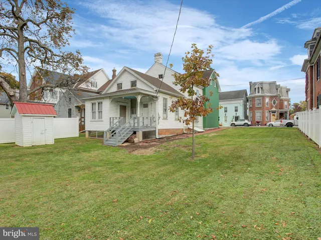 a view of a white house with a big yard and potted plants