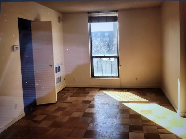 a view of an empty room with wooden floor and closet