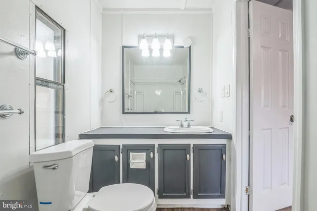 a bathroom with a granite countertop toilet a sink and a large mirror