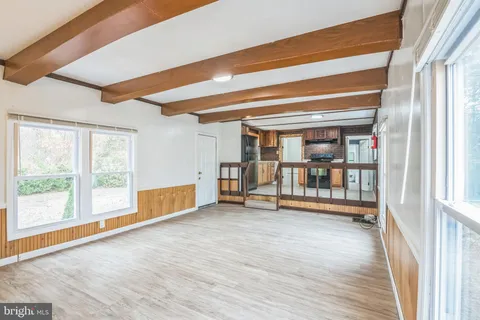 a view of an empty room with wooden floor and furniture