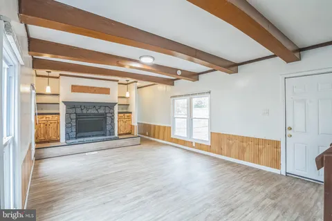 a view of an empty room with wooden floor fireplace and a window