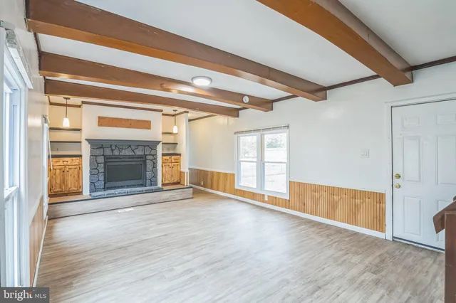 a view of an empty room with wooden floor fireplace and a window