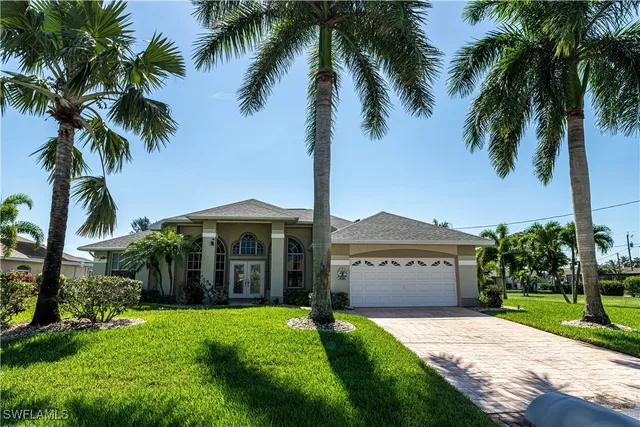 a front view of a house with a garden and palm trees