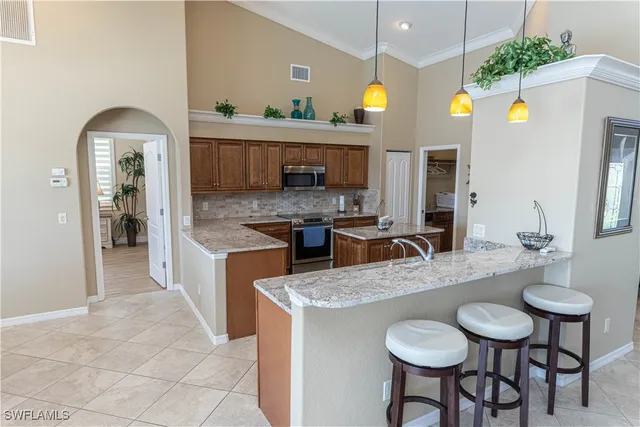 a kitchen with stainless steel appliances granite countertop a sink a stove and chairs