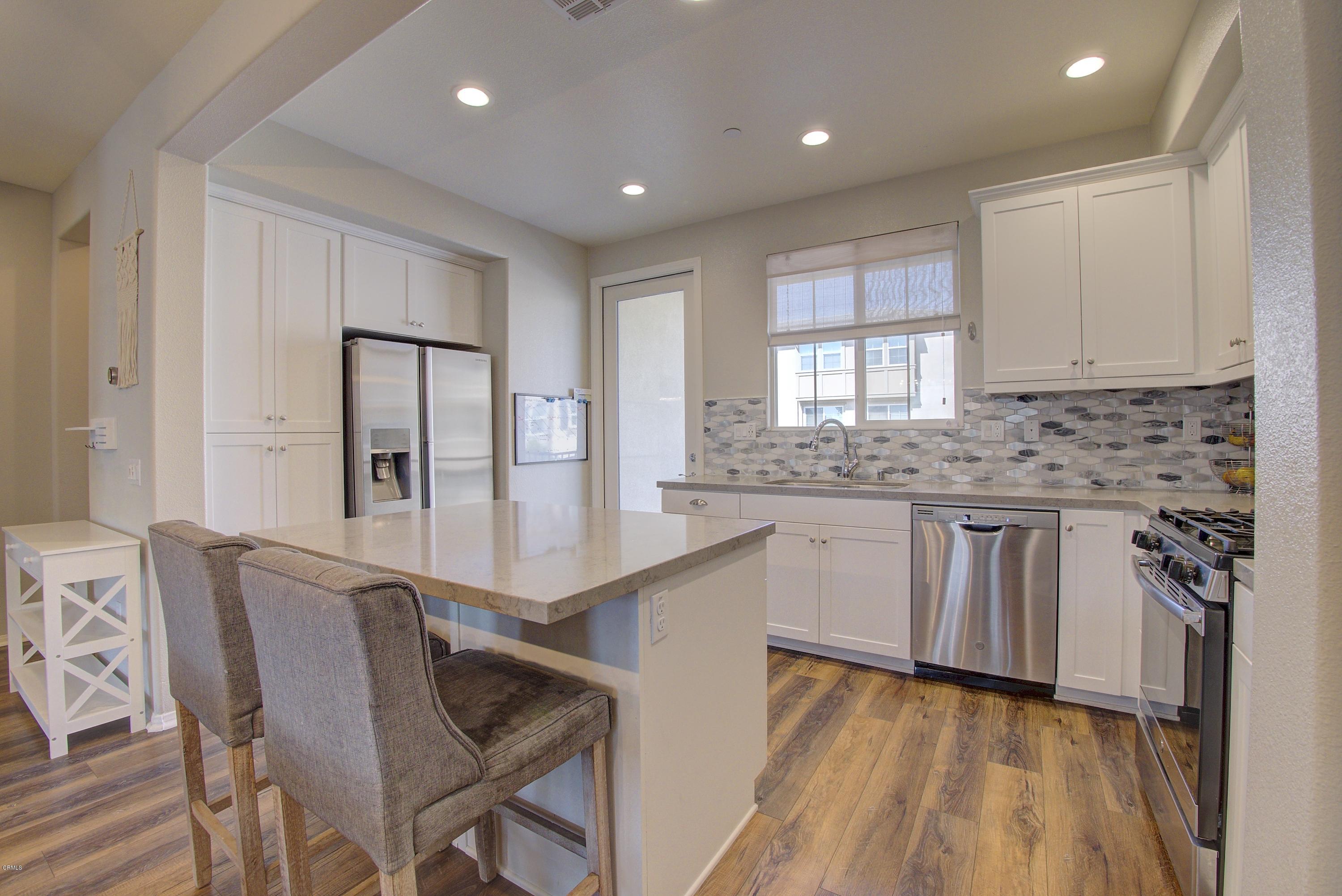 178 Prairie Street Camarillo, CA 93010 - Photo 16 of 74 a kitchen with granite countertop white cabinets a refrigerator a sink a stove and wooden floors