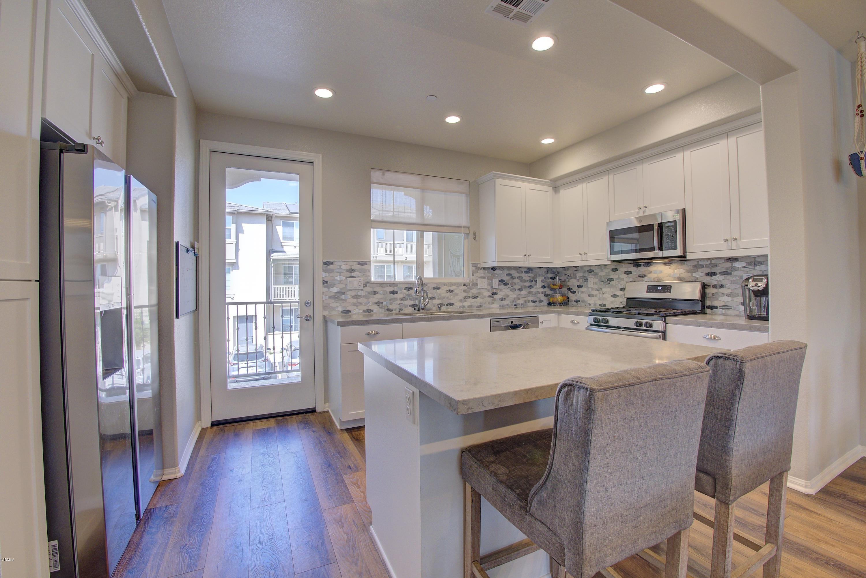 178 Prairie Street Camarillo, CA 93010 - Photo 18 of 74 a kitchen with kitchen island granite countertop wooden floors white cabinets and stainless steel appliances