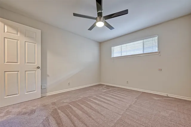 an empty room with windows and ceiling fan