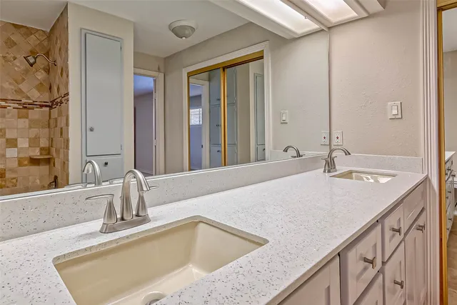 a spacious bathroom with a double vanity sink a mirror and a shower