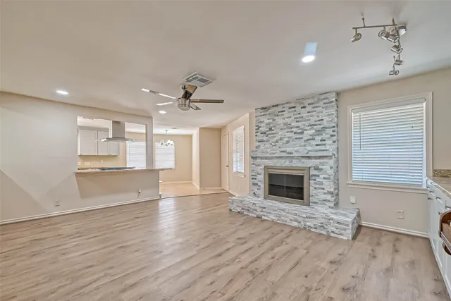 an empty room with wooden floor fireplace and windows