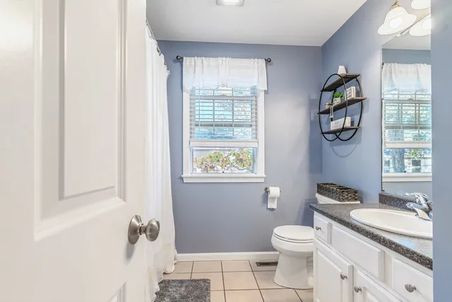 a bathroom with a granite countertop toilet a sink and a window
