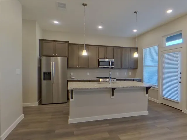 a kitchen with kitchen island a sink stainless steel appliances and refrigerator