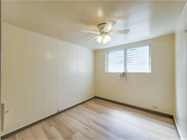 a view of empty room with wooden floor and fan